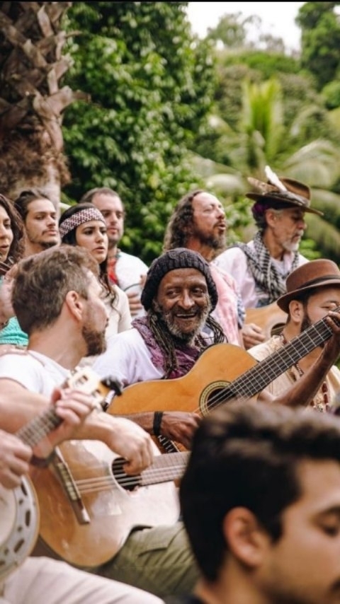 Leal Carvalho sorrindo ao centro de uma roda de músicos e amigos
